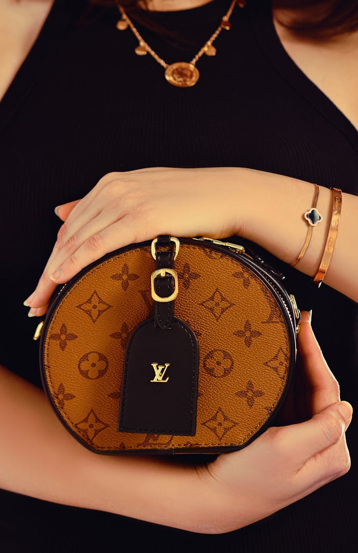 A close-up of a brown designer handbag held by a woman, showcasing luxury fashion.